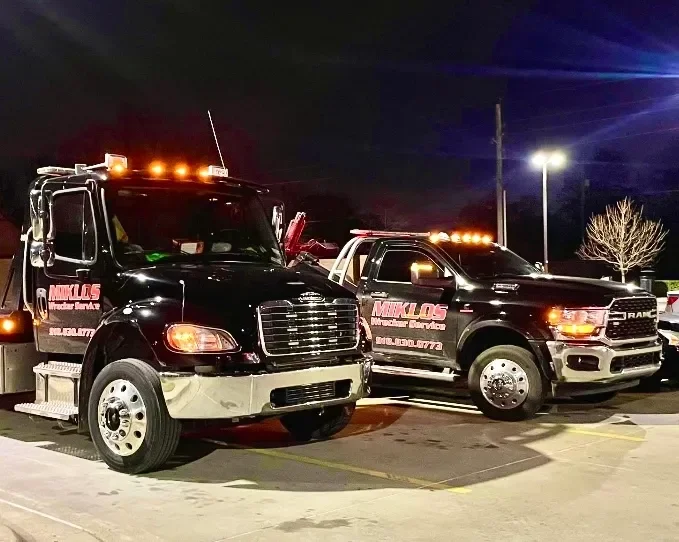 Two Miklos tow trucks parked at night